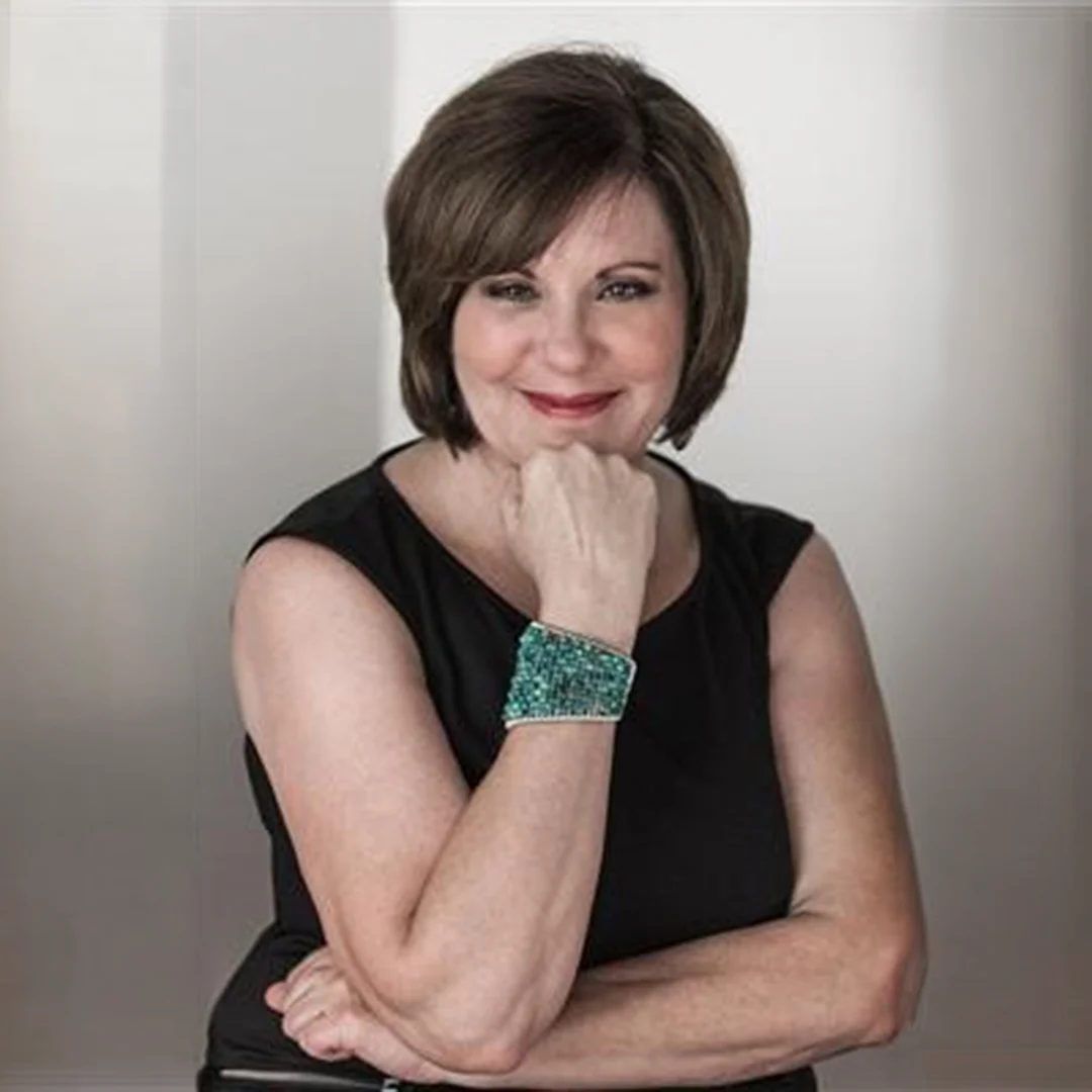 Portrait of Danielle Whitmore smiling with hand resting under chin in a professional headshot setting